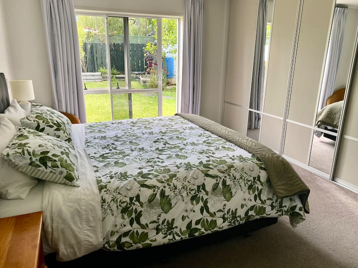 Cama tamaño king con puertas correderas hacia el jardín trasero. 
