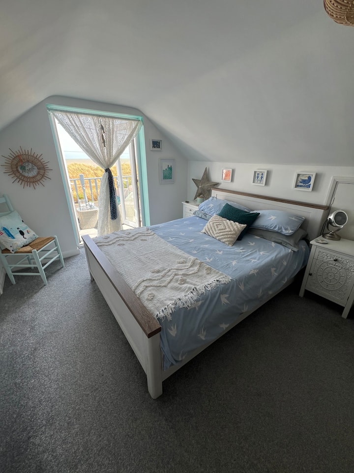 מיטת קינג סייז בקומה הראשונה עם מרפסת ונוף לחוף הים.