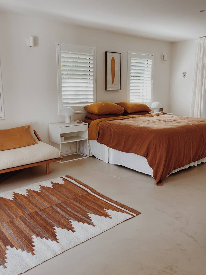 Chambre principale avec très grand lit, télévision et canapé pour se détendre