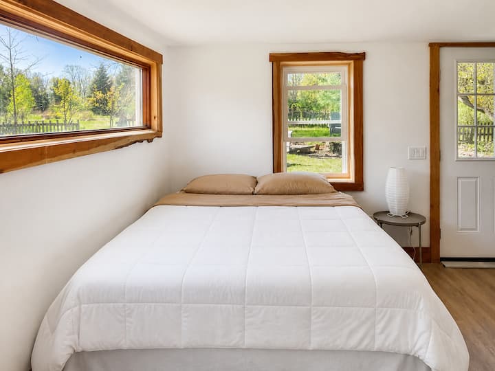 The comfy queen-size bed downstairs in an open floor plan. The downstairs is set up like a studio apartment, open to the living space and kitchen.