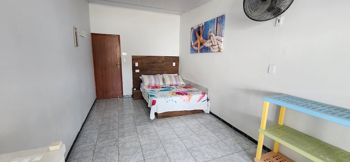 HABITACIÓN 4: cama doble muy grande, aire acondicionado, ventilador de pared, espejo, ventilador móvil y estante para objetos.