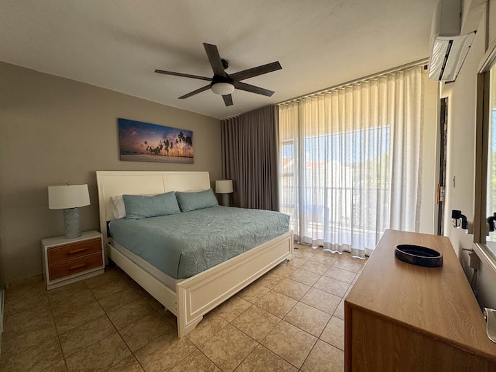 וילונות האפלה ופרטיות אלגנטיים. חדר שינה ראשי בגודל קינג סייז עם מרפסת פרטית וחדר רחצה פרטי. דלתות ארון מראה