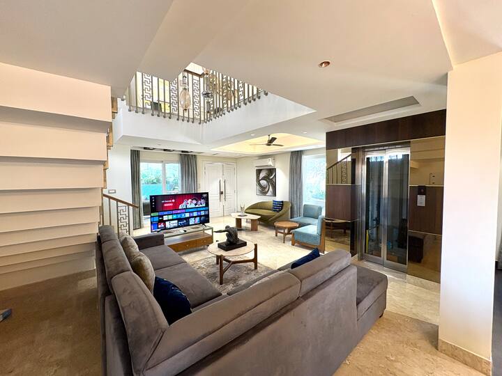 Experience ultra-luxury 4BHK villa living with a grand double-height living room, plush seating, and