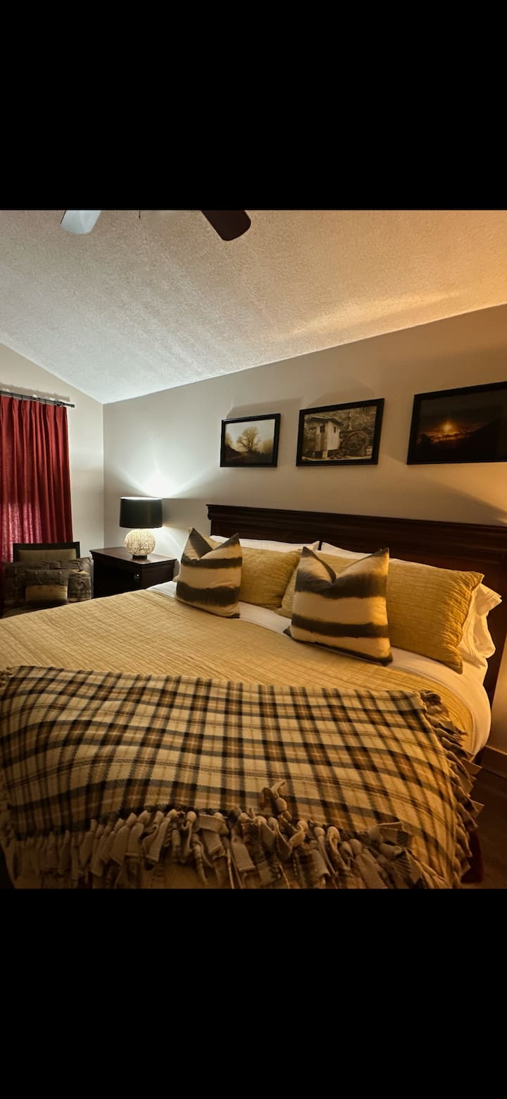 California king primary bedroom has it’s own bath and two oversized chairs for your private seating area. 65 inch television. Charging outlets on both sides of the bed. ￼ Large highboy dresser, and an additional large storage nightstand. 