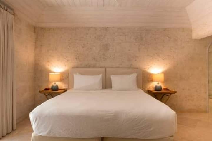 A charming en suite bedroom with ample clothes storage, ceiling fan and air conditioning.