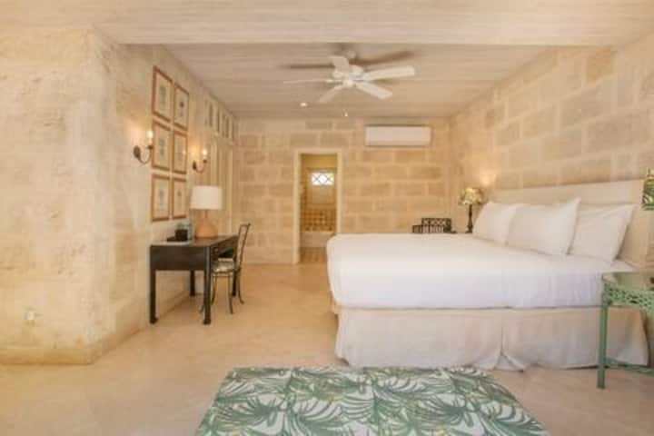 An elegant en suite bedroom with ample clothes storage, ceiling fan and air conditioning.