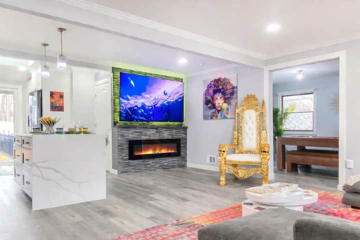 תוכלו להירגע בסלון הפתוח הזה, שכולל קיר אח תוסס עם טלוויזיה חכמה בגודל 86 אינץ', אי מטבח אופנתי, כיסא כס המלכות הזהוב ומקומות ישיבה נעימים. אווירה צבעונית ומלאת אמנות זורמת דרך החלל - מושלם לשהייה וקבלת אורחים.