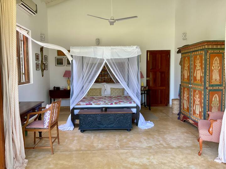 Segundo dormitorio con cama tamaño king con cuatro postes, armario, estante colgante, escritorio/tocador y cómodo sillón. Incluye aire acondicionado y ventilador.