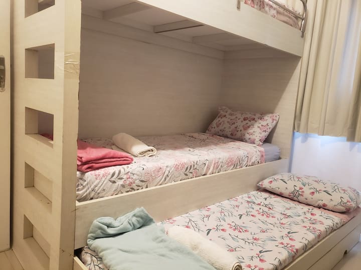 Bedroom with fan with 4 beds, one of which is a trundle bed designed in high design