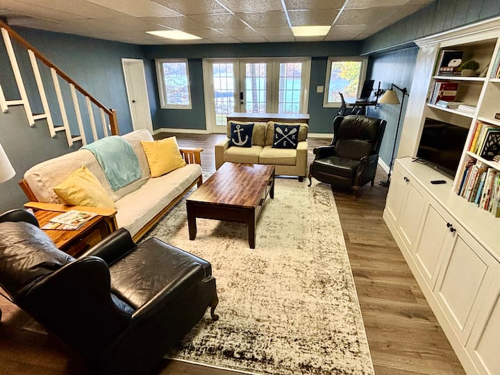 Sala de estar en el sótano con TV inteligente, futón y escritorio