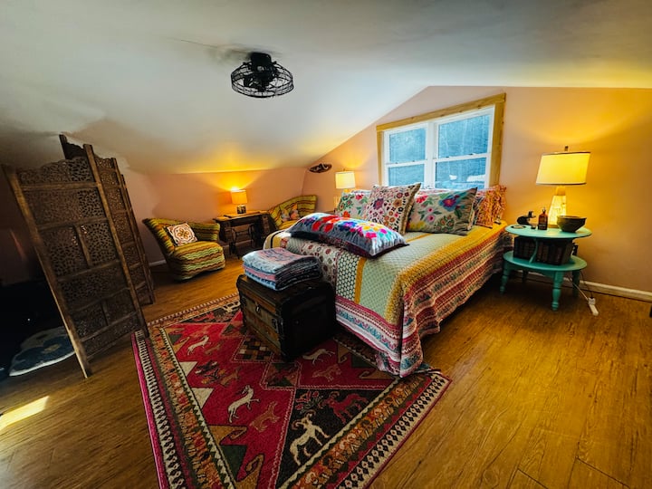 ที่นอนเมมโมรี่โฟมใหม่พร้อมผ้าปูที่นอนผ้าฝ้ายสุดหรูและหมอนระดับพรีเมียม อ่างอาบน้ำครึ่งหนึ่งอยู่ภายในห้องที่มีหน้าจอความเป็นส่วนตัวทีวี Roku ขนาด 55 นิ้วบนขาตั้งเพื่อให้สามารถดูตัวเลือกได้ 