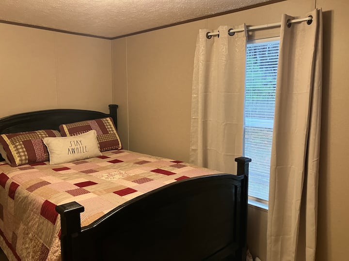 Queen ‑ ის საწოლი ტუმბოებით, 32-დუიმიანი Roku ‑ ს სმარტ-ტელევიზორით. Მოყვება უშუქო ფარდები და კარადა ტანსაცმლის დასაკიდად.