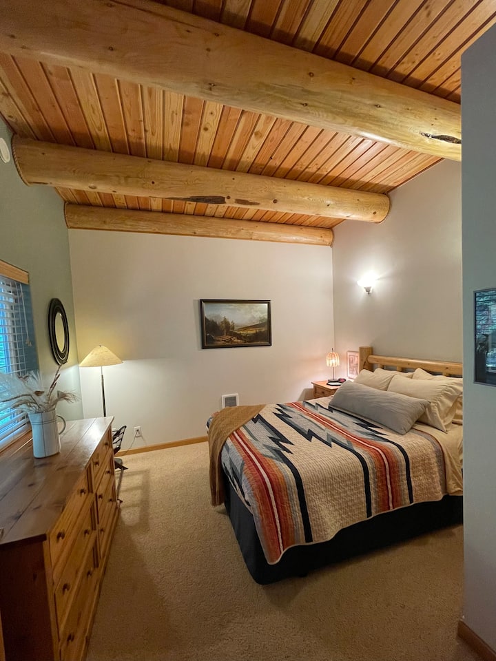 Main floor bedroom #2 with a Queen bed, closet, and chest of drawers.