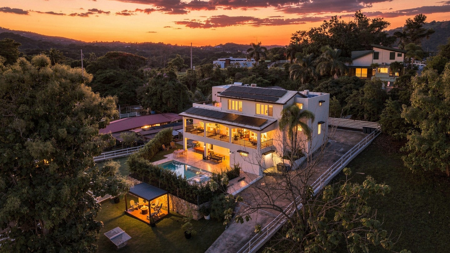 Hero: aerial twilight view of villa with lit pool and mountains