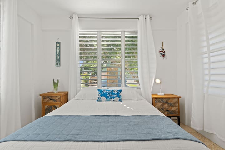 Bright bedroom with airy windows, nautical decor, and inviting blue accents!