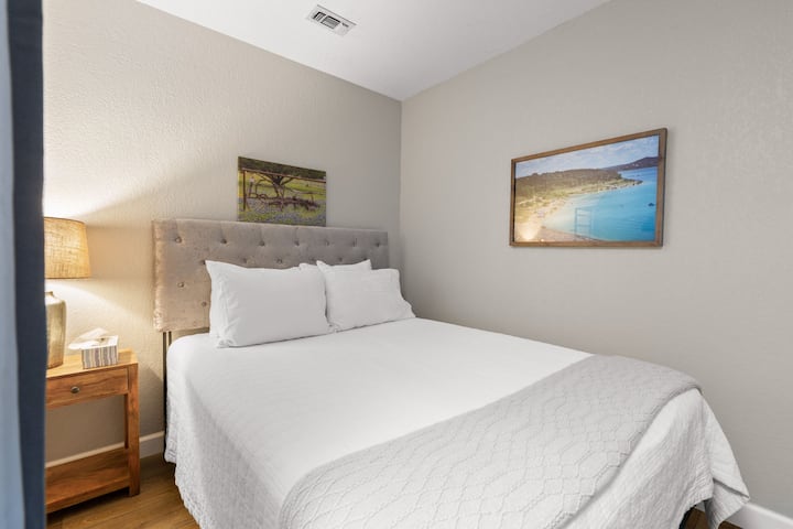 Bedroom 4 includes (4) private sleeping spaces. Each with 3 walls, curtain, tower fan, night stand with lamp, clothing rack or dresser, and luggage rack. Queen shown here.