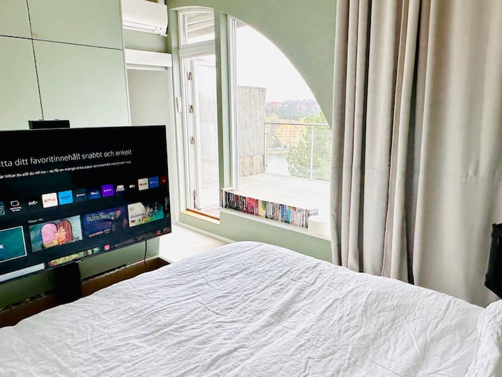 Det stora sovrummet på egen våning med 20 kvm terrass med solnedgång. 42" smart-TV i en låda vid sängen.