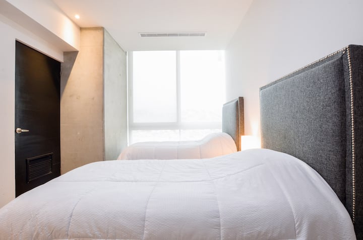 Recámara terciaria con 2 camas individuales, plancha y burro de planchar, área de trabajo, clóset con ganchos y clima (AC), en un espacio pensado para tu comodidad durante tu estancia.