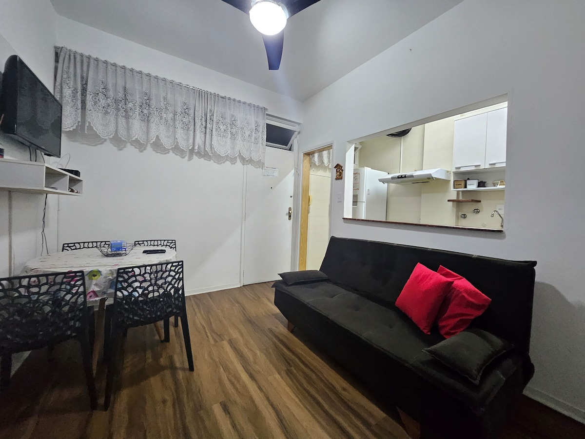 Habitación con TV inteligente, mesa redonda, 6 sillas, sofá cama y ventilador de techo.