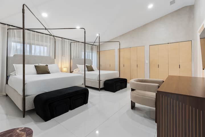 Dva luksuzna bračna kreveta s baldahinom i zavjesama od poda do stropa za miran odmor.