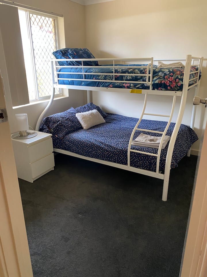 Litera doble, individual en la parte superior, mesita de noche y lámpara 