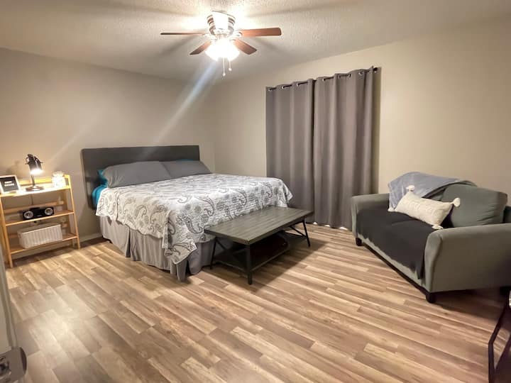 Amplio dormitorio orientado al sur con colchón King y un pequeño sofá de dos plazas, ¡perfecto para prepararte para tu día!