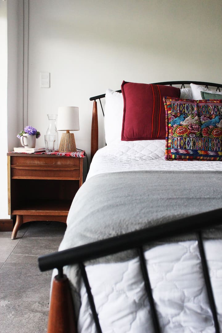 Chumba chenye kitanda aina ya queen na kiti cha mikono, kilichobuniwa kwa ajili ya kupumzika baada ya siku nzima huko Atitlán. Kwenye ghorofa ya pili, inaunganisha kwenye bafu la pamoja na roshani ya kujitegemea yenye mandhari ya kipekee ambayo hufanya kila uamko ukumbukwe.