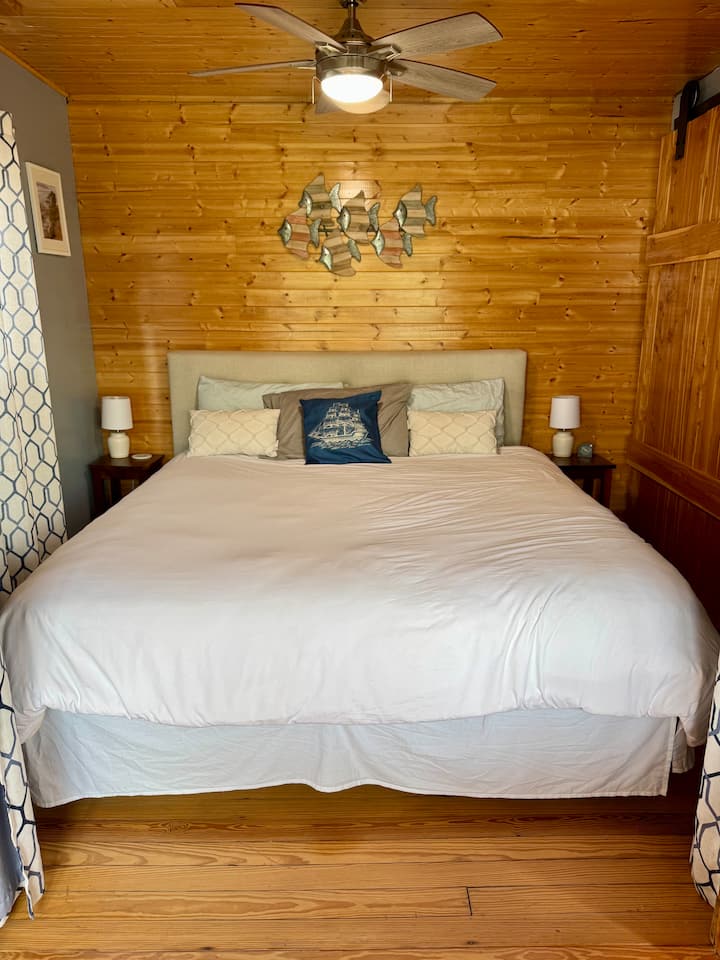 The king-size bed bedroom has privacy curtains that open to the dining room and provide views of the water.