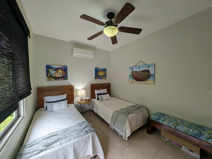 Perfect for families, this cheerful guest room features two twin beds, whimsical ocean art, and its own dedicated AC and ceiling fan.