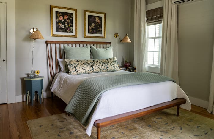 The first floor guest bedroom adjoins the airy sunroom at the front of the home and hosts a desk.