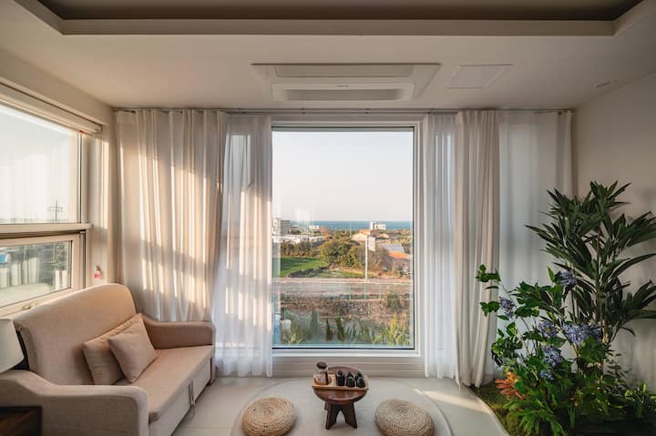 A floor-seating tea ceremony space by the window in the bedroom. It includes a comfortable armchair and a tea set, allowing you to enjoy the warm sunlight streaming through the floor-to-ceiling windows.