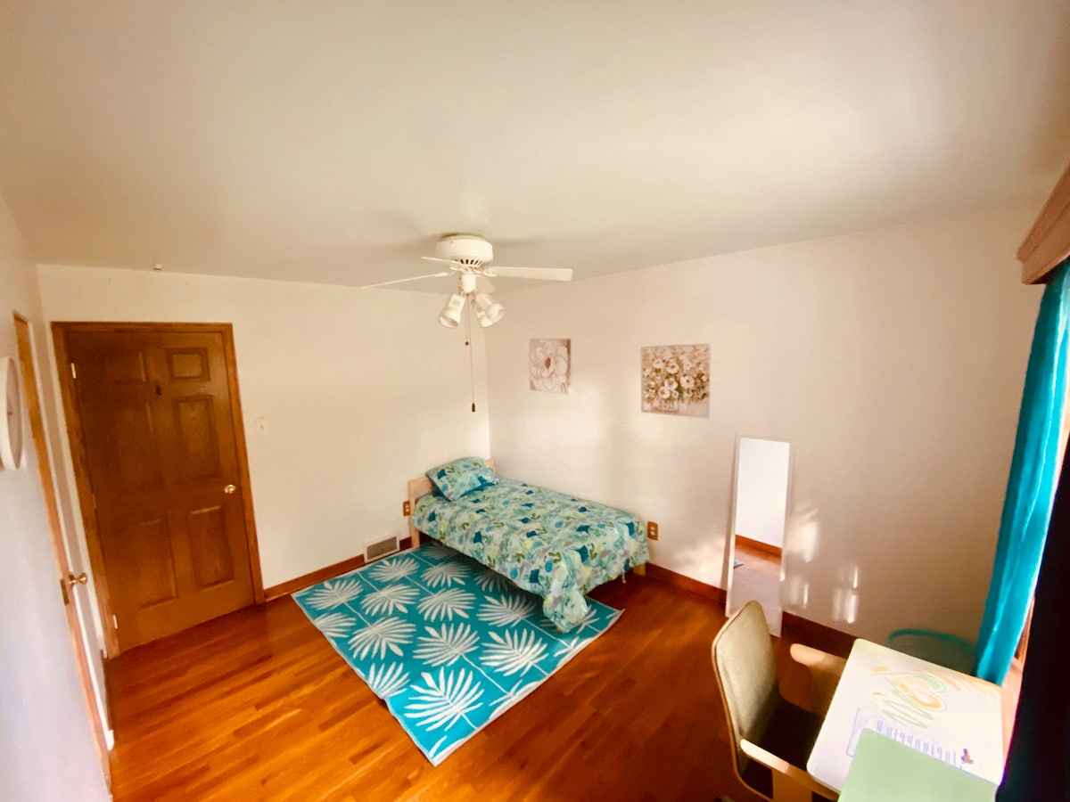 Dormitorio espacioso y luminoso con mucha luz natural, con una gran ventana que ofrece una vista impresionante del hermoso patio trasero. Incluye un armario, un espejo y un escritorio acogedor con una silla, por lo que es un refugio perfecto para relajarse e inspirarse.