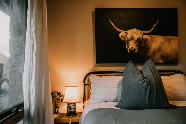 Snuggle up beneath the cow's watchful gaze—mountain serenity awaits.