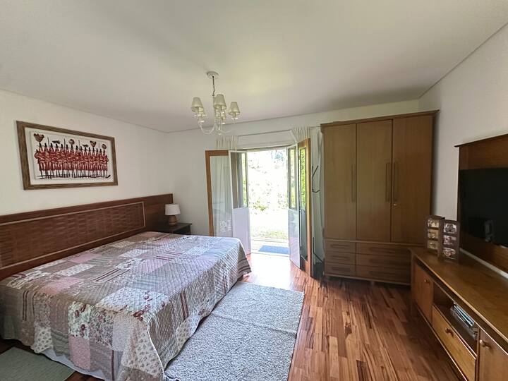 1. suite - stueetagen - med kingsize-seng + balkondør med udgang til haven og udsigt over Araucaria-skoven; der er en dør med myggenet.