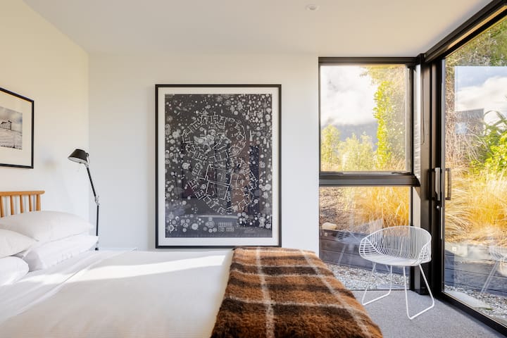 An attractive ground floor bedroom with Queen size Ercol bed, Tolomeo bedside lamps, wool rug, wardrobe and art.