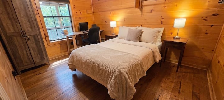 Small downstairs bedroom with full bed (1 of 2 downstairs bedrooms), comfortable desk and office chair with view of forest