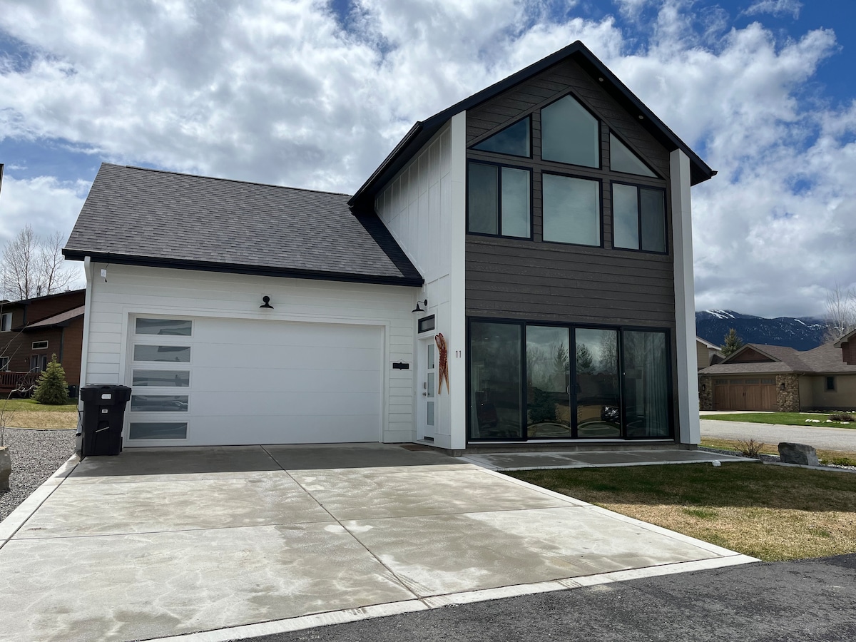 The modern townhouse features a two-story design with large windows allowing natural light to flood the interior. An attached garage provides convenient parking. A spacious driveway and well-maintained yard complement the exterior.