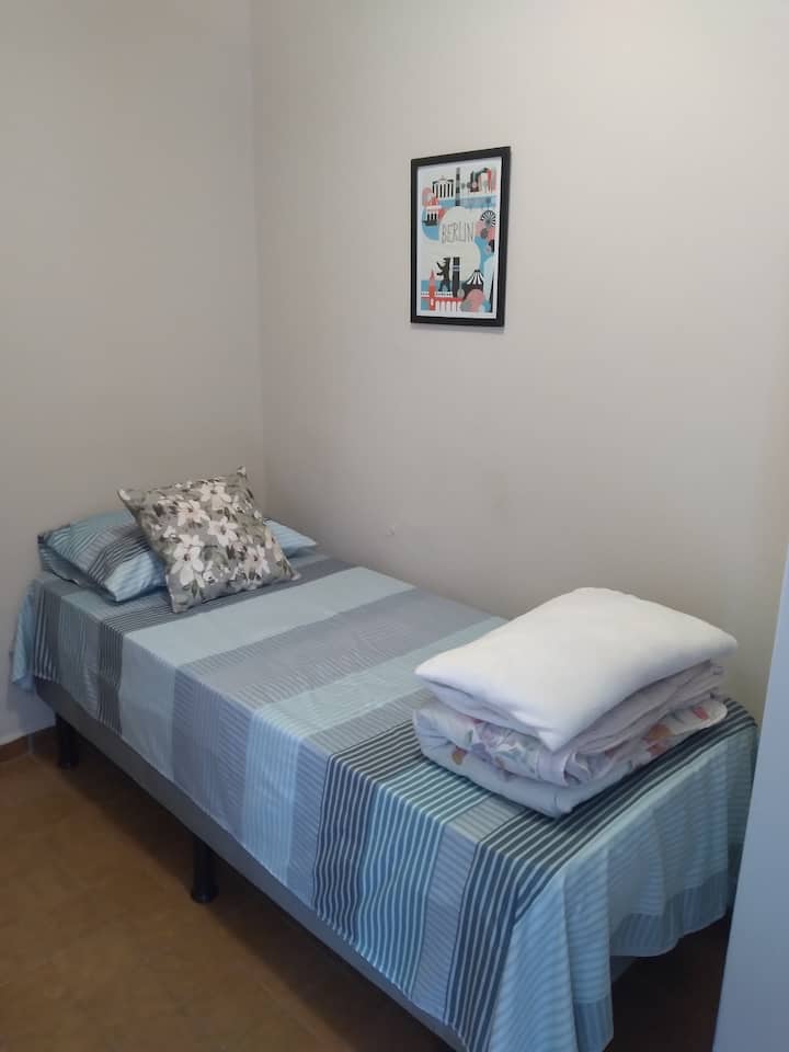 Spavaća soba s jednim krevetom, ormarom s 2 vrata i ventilatorom. 