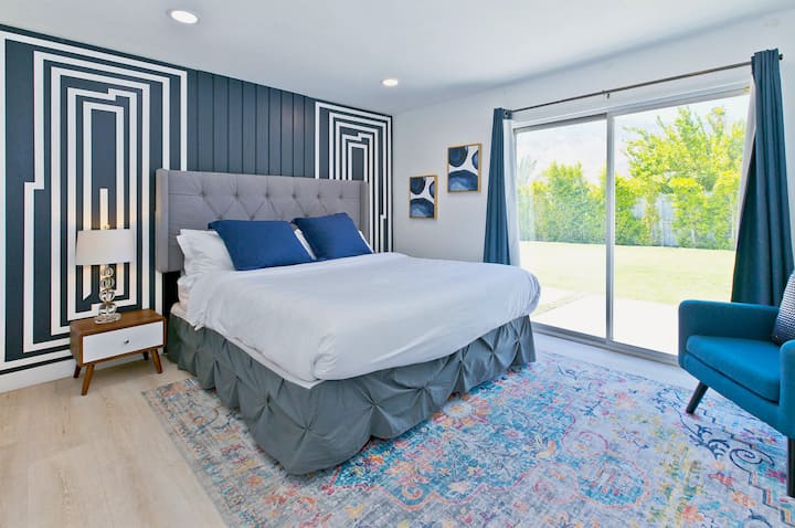 Chambre lumineuse avec tête de lit originale, sièges confortables et portes coulissantes qui s'ouvrent sur l'air frais.