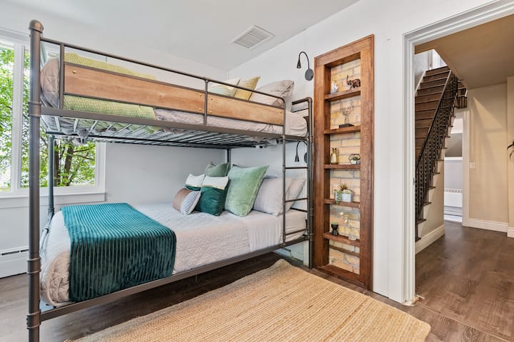 Exposed brick from the original home gives this room charm and style!
Two queen beds, dresser, and 42 inch Roku TV. Three large windows fill the room with ample natural light.