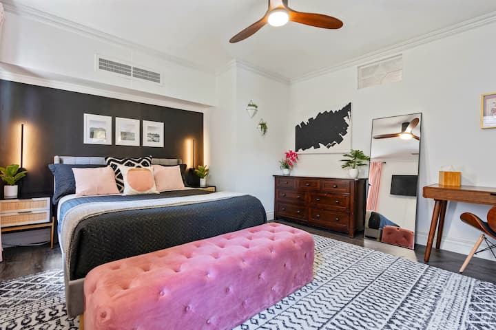 Chic bedroom with queen bed, dresser, desk, and large resting bench 