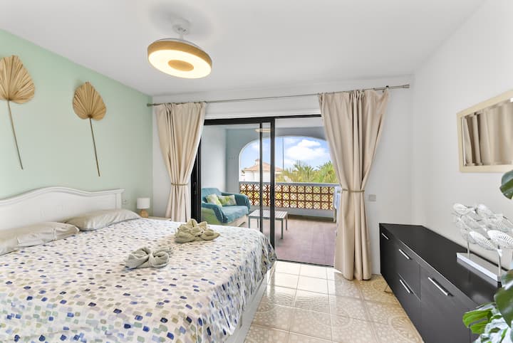 Главна спалня със собствена баня и красива тераса с изглед към океана и голф игрището, разположена на приземния етаж на ваканционния дом. 