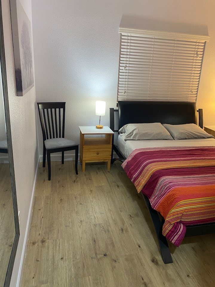 Small bedroom with queen bed and hardwood floors.