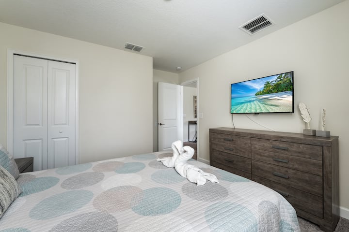 Comfortable guest bedroom with a view of the TV, designed for peaceful rest and quiet downtime.