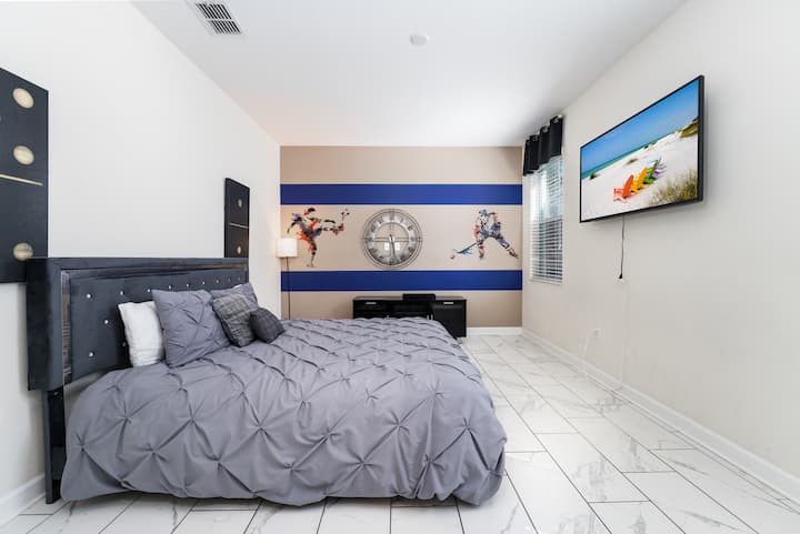 Spacious guest bedroom with a modern aesthetic, featuring premium linens and a large flat-screen TV for added comfort.