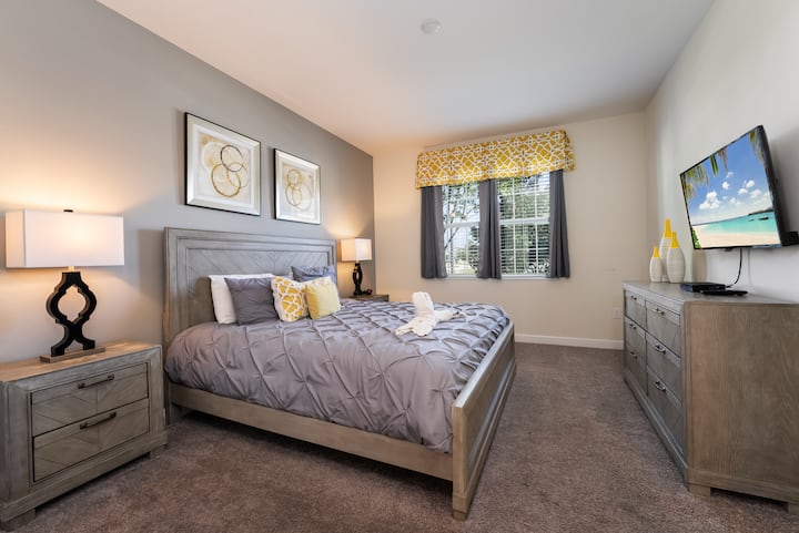 Comfortable master bedroom with plush bedding, neutral decor, and plenty of natural light for a restful stay.