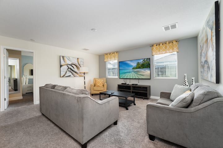 Spacious family room with plush sofa seating and a large flat-screen TV, ideal for movie nights and family relaxation.