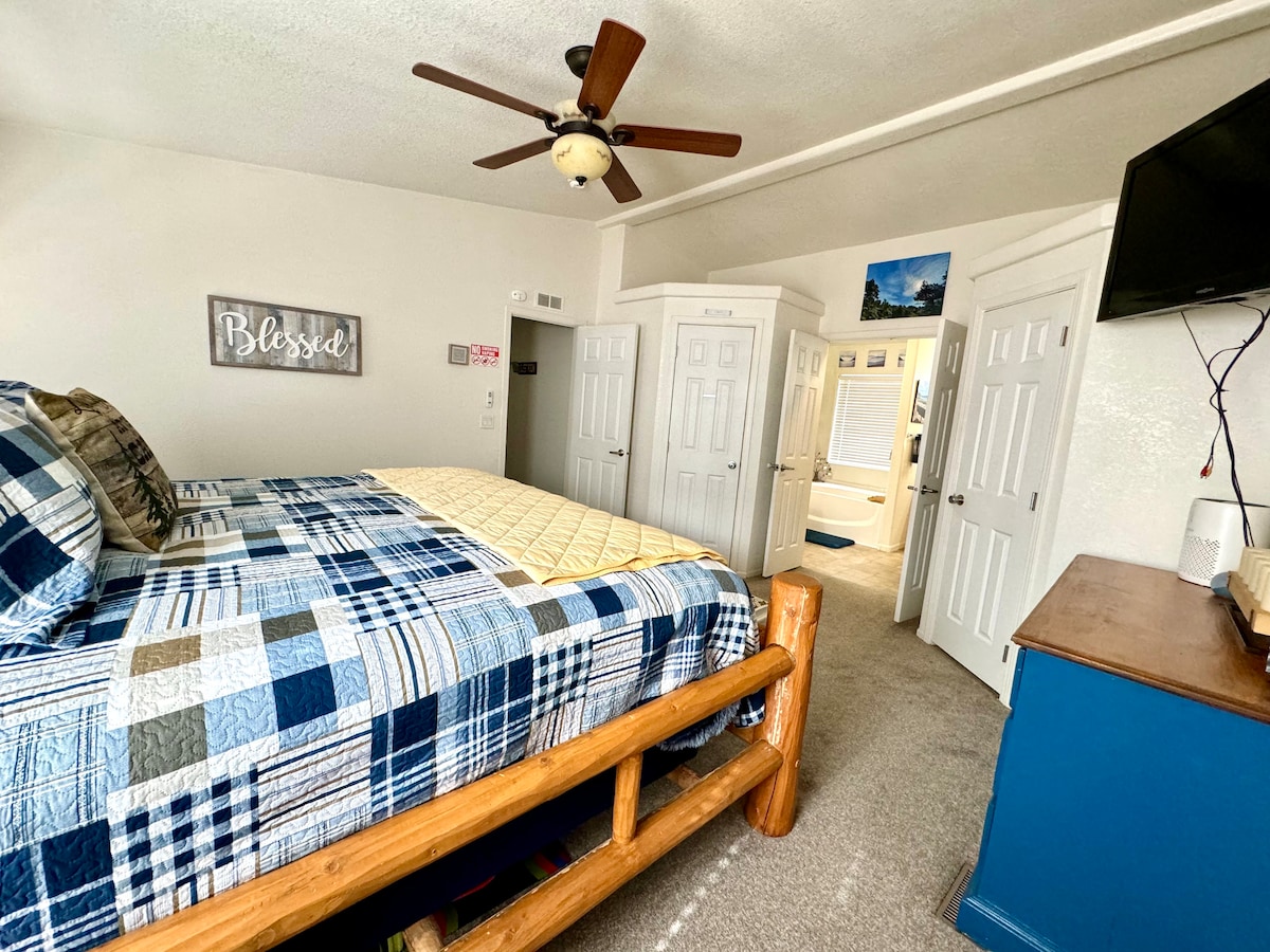 The primary bedroom at Almost Bearadise Cabin invites you to unwind on a king-size luxury bed with premium bedding. Refresh and relax in the en-suite bathroom featuring a large soaking tub, dual vanities, and a separate shower—pure bliss awaits.