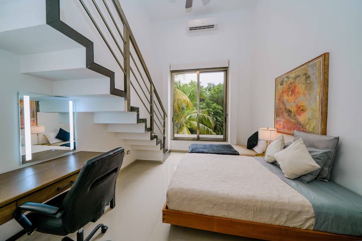 Recámara moderna y luminosa con espacio de trabajo, escalera tipo loft y vistas tropicales