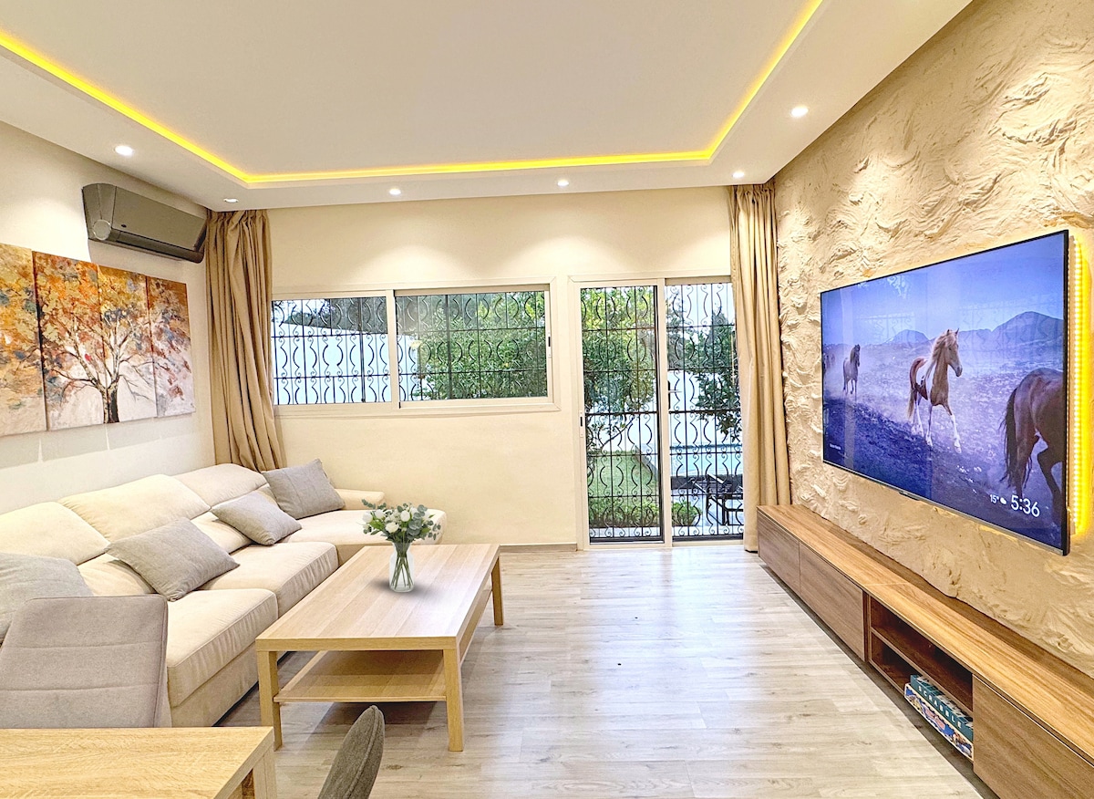 Пространа и светла дневна соба, опремена со 65-инчен телевизор со Netflix, Prime Video, Disney+ и YouTube. Клима уред и греење за оптимална удобност. Директен пристап до градината со непречен поглед кон базенот, идеален за моменти за опуштање со семејството.